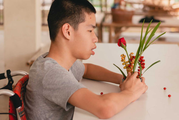 jung-im-rollstuhl-schaut-blumen-an